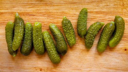 Full shot of some tiny pickled cucumbers in a wooden cutting board