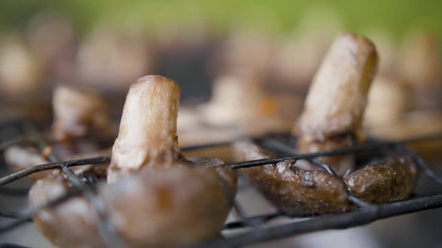 Mushrooms brown champignon cooked on grill or barbecue outdoors