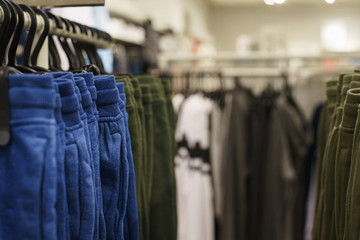 Hoodies, a sweater and a hoodie on a hanger in a fashion store for youth.
