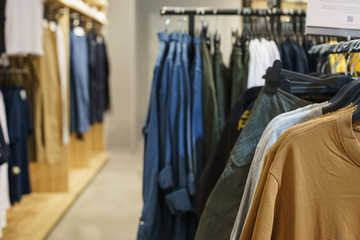 Hoodies, a sweater and a hoodie on a hanger in a fashion store for youth.