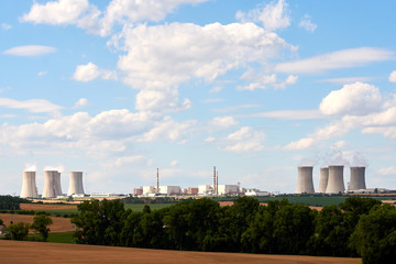 View of the smoking chimneys of a nuclear power plant in the landscape with trees, fields and...