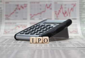Initial Public Offering on wooden cubes with calculator on a busibess newspaper