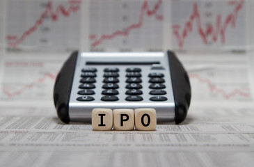 Initial Public Offering on wooden cubes with calculator on a busibess newspaper