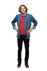 Fototapeta premium Full-length shot of Blonde man posing with arms at hip and smiling over isolated white background