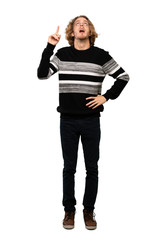 Full-length shot of Blonde man pointing up and surprised over isolated white background