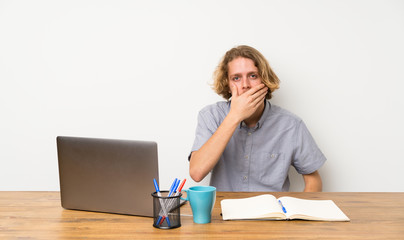 Blonde man with a laptop covering mouth with hands