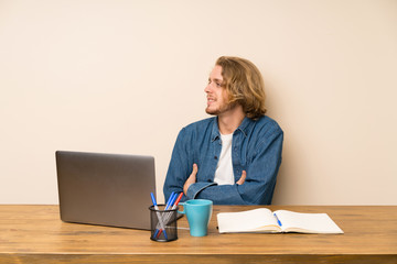 Blonde man with a laptop looking to the side