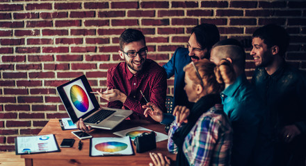 team of designers in the workplace in front of an open laptop di