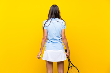 Young tennis player woman over isolated yellow wall
