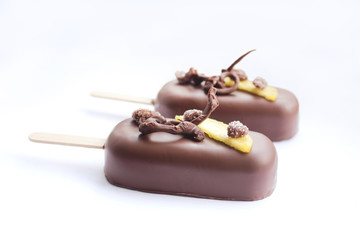 Chocolate glazed peach ice cream popsicles with chocolate decoration