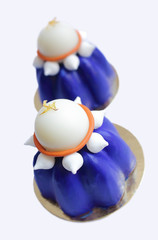 Two blue blueberry mousse desserts with white chocolate and meringues