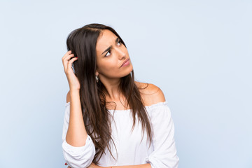 Fototapeta premium Young woman over isolated blue background having doubts and with confuse face expression