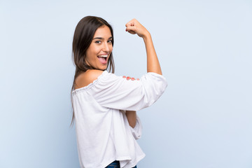 Young woman over isolated blue background making strong gesture