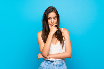 Young woman over isolated blue background thinking