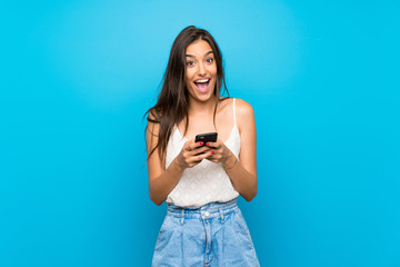 Young woman over isolated blue background surprised and sending a message