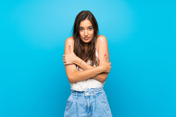 Young woman over isolated blue background freezing
