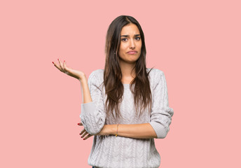 Young hispanic brunette woman unhappy for not understand something over isolated background