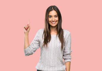 Young hispanic brunette woman showing and lifting a finger in sign of the best over isolated background