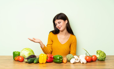 Fototapeta premium Teenager girl with many vegetables holding copyspace with doubts