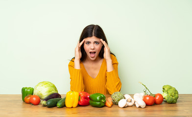 Fototapeta premium Teenager girl with many vegetables with surprise expression