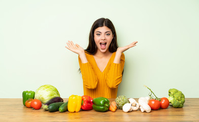 Fototapeta premium Teenager girl with many vegetables with shocked facial expression