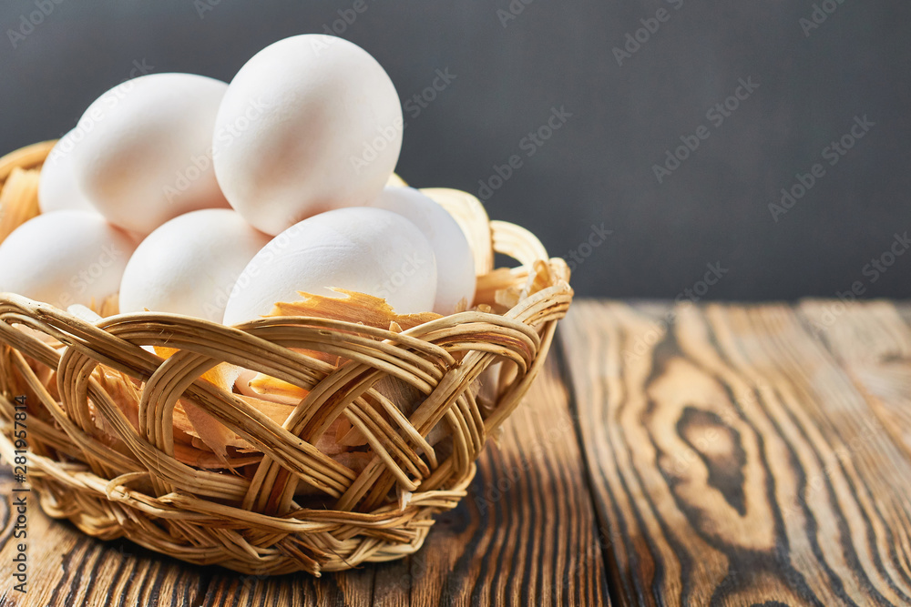 Canvas Prints Basket with sawdust full of chicken eggs lies on rustic wooden table. Space for text