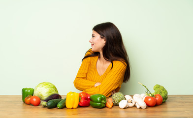 Teenager girl with many vegetables in lateral position