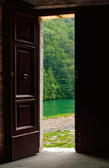 Old door opened viewing a lake