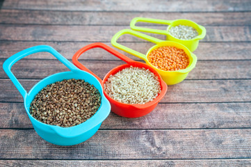 Collection of different cereals  in multi-colored containers, Oatmeal buckwheat, barley and rice