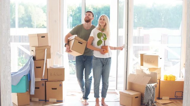 Happy young Couple Carrying Cardboard Boxes Into New Home On Moving Day