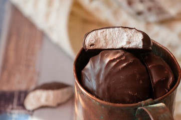 Chocolate marshmallows in mint cup. on a wooden table