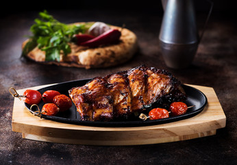 Grilled pork ribs, fresh herbs and baked tomatoes on a serving board