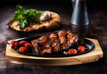 Grilled pork ribs and baked tomatoes on a serving board