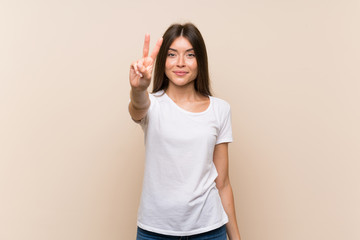 Pretty young girl over isolated background smiling and showing victory sign
