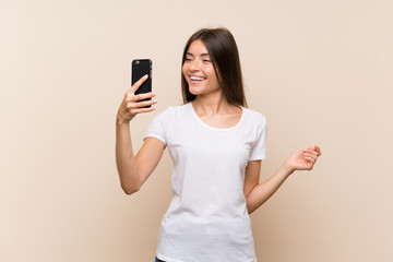 Pretty young girl over isolated background making a selfie