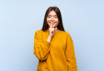 Caucasian young woman over isolated blue wall doing silence gesture