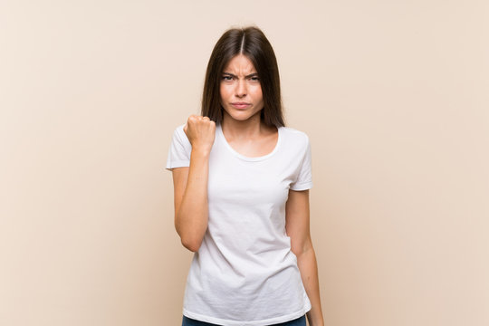 Pretty young girl over isolated background with angry gesture