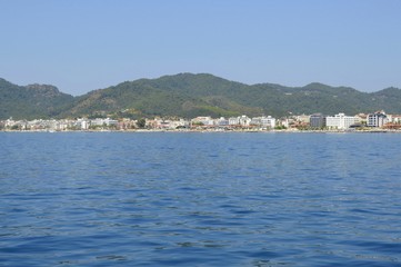 Fototapeta na wymiar View of the embankment of the city of Marmaris from the sea. City-port and resort in Turkey. Sandy beaches, mountain landscapes.