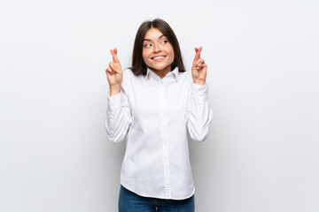 Young woman over isolated white background with fingers crossing