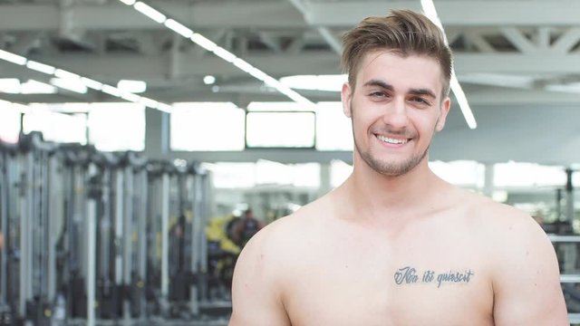 Portrait of young sports guy in the gym looking at camera.