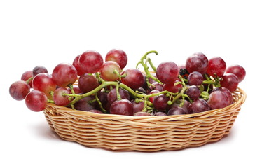 Fresh red grapes in wooden wicker basket isolated on white background