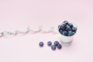 Summer blueberries in bucket on pink background. Berries for design. Close up top view or flat lay with place for your text. Concept medical diet