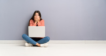 Young student girl with a laptop on the floor with surprise facial expression