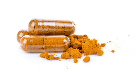 herb turmeric capsules spilling on white background