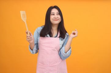 Happy Asian woman is cooking with apron for cooking advertise theme on on yellow background.