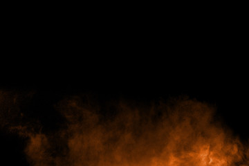 Abstract orange powder explosion on black  background. Freeze motion of orange  dust particles...