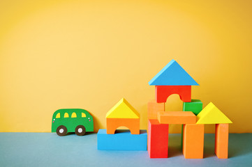 Cars cut out of paper and houses from cubes on a yellow background. Educational toys for preschool...