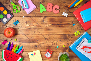 Back to school background with school supplies on wooden table. Top view from above