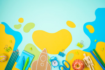 Back to school concept with school supplies and paper flowing shapes background. Top view from above