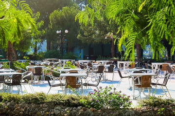 Free tables and chairs of a summer restaurant on the terrace, in the open air. Empty tables of the summer restaurant of the hotel.
